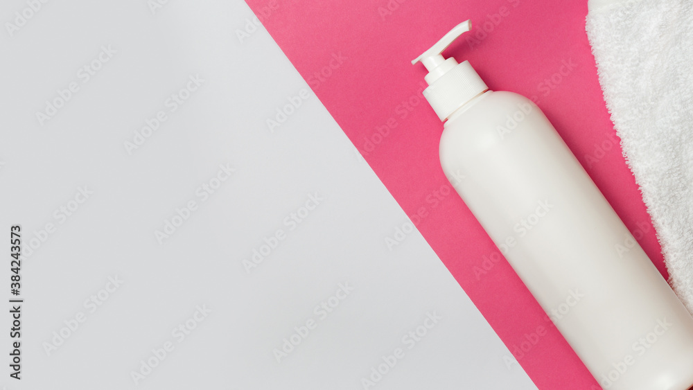 Soap bottle and shower sponge on white and pink background with copy space Soap bottle and shower sponge on white and pink background with copy space