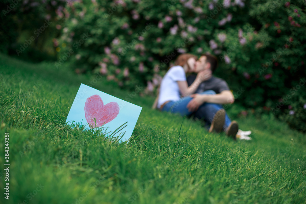 Couple in love with a card with red heart in nature. love story concept.  romantic date in nature. romantic moment in background in sring green park.  greeting card for valentines day Stock
