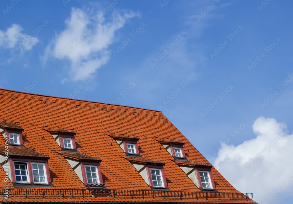 Red tile roof with Dormer Windows against a background of blue sky and clouds on a bright Sunny day.Urban European architecture of the old town