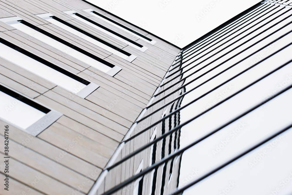 Obraz premium The combination of wood and glass textures on the facade of a modern multi-storey building creates a minimalistic, stylish and geometric pattern. Urban abstract futuristic architecture