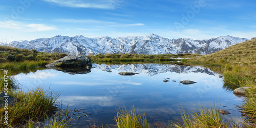 Panorama eines Sees in den Alpen mit verschneiten Bergen im Hintergrund