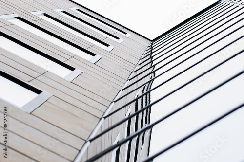 The combination of wood and glass textures on the facade of a modern multi-storey building creates a minimalistic, stylish and geometric pattern. Urban abstract futuristic architecture