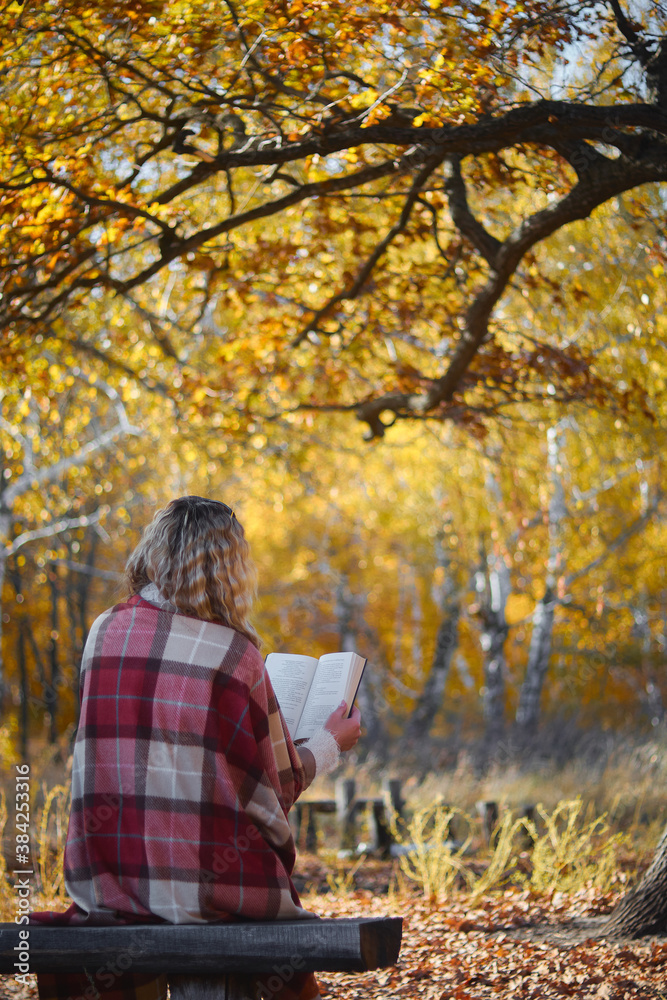 Beautiful european woman in autumn park sitting under a tree and reading a book Beautiful european woman in autumn park sitting under a tree and reading a book