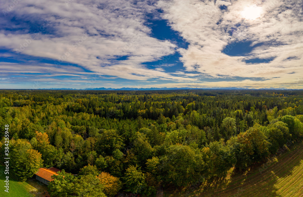 A beautiful view over a green forest at the early autumn with an idyllic house in the foreground, shot by a drone. A beautiful view over a green forest at the early autumn with an idyllic house in the foreground, shot by a drone.