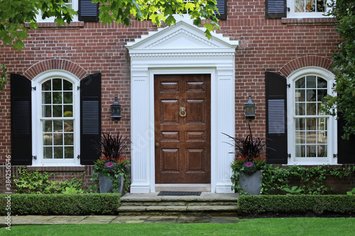 Elegant wooden front door of  traditional brick two story suburban middle class home
