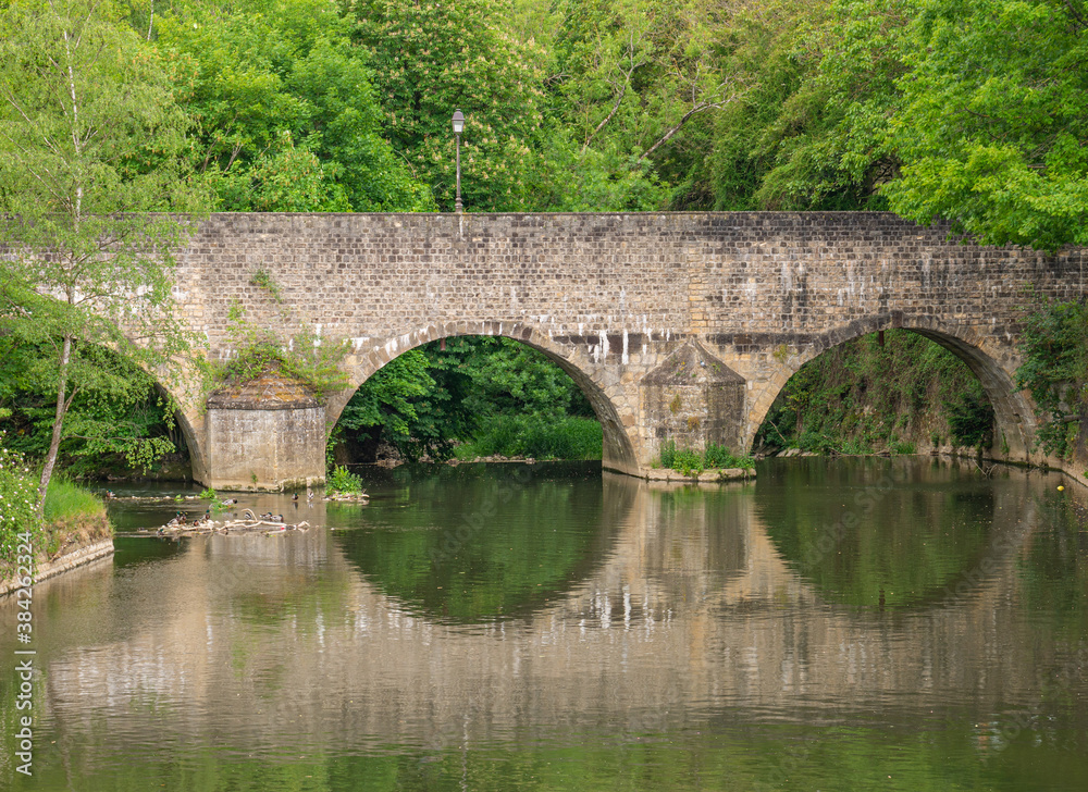 Eine alte Steinbrücke spiegelt sich im Wasser