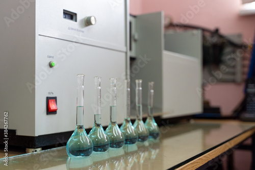 Εκτύπωση καμβά Row of volumetric flasks on a laboratory table with blue liquid inside