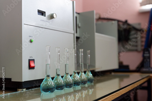 Row of volumetric flasks on a laboratory table with blue liquid inside