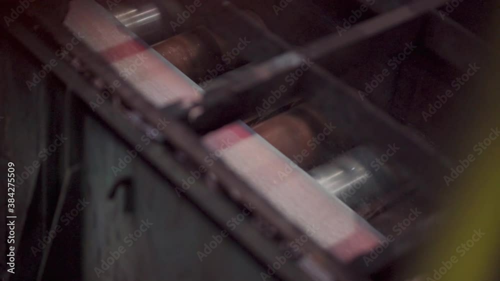 The hot sheet of metal moves on the conveyor. Slow motion. The hot sheet of metal moves on the conveyor. Slow motion.