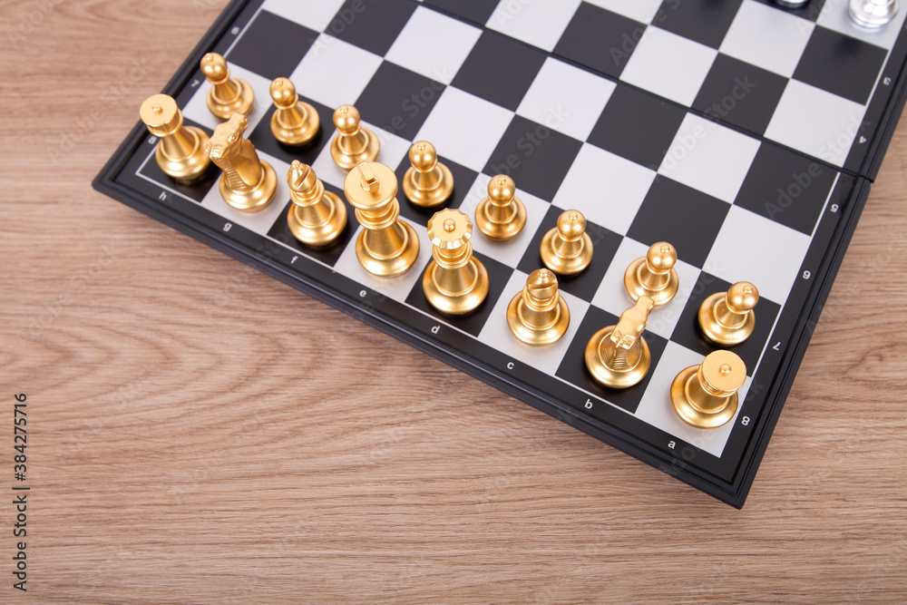 Looking down shot of golden chess pieces on a checkered chessboard