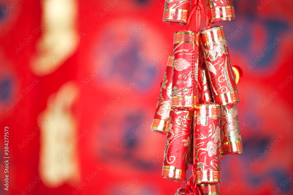 Red firecracker pendant hanging in front of red spring couplets background