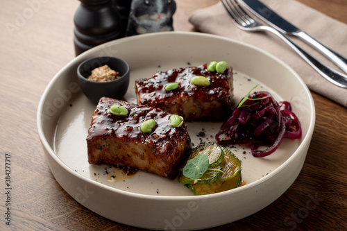 Appetizing commercial food photo of vegetarian meal: roasted tofu steak with edamame, sort light and shadows, wooden table in a restaurant