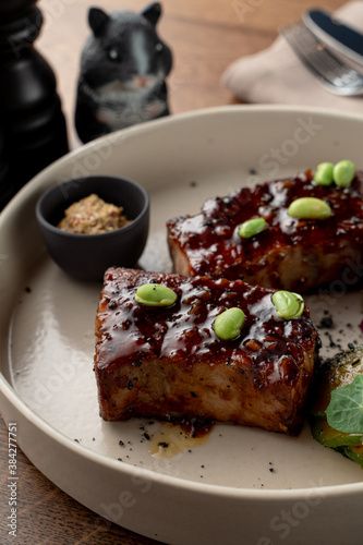Teriyaki sauce crab cakes, glazed and spicy with edamame beans, close up on wooden background in soft light, fancy restaurant photo