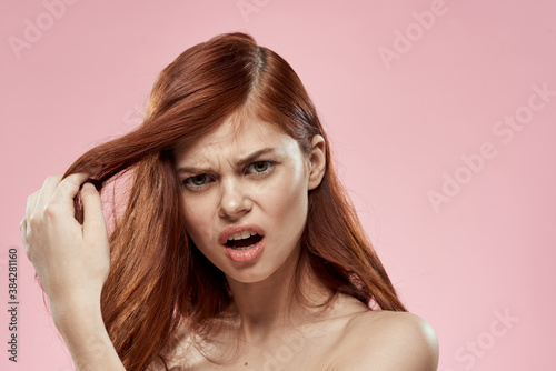 woman holding hair with hand problems hairstyle care emotions bare shoulders pink background