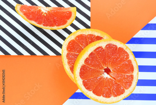    fresh slices of red grapefruit on a multicolor background, minimalism, vitamins, healthy diet food concept      photo