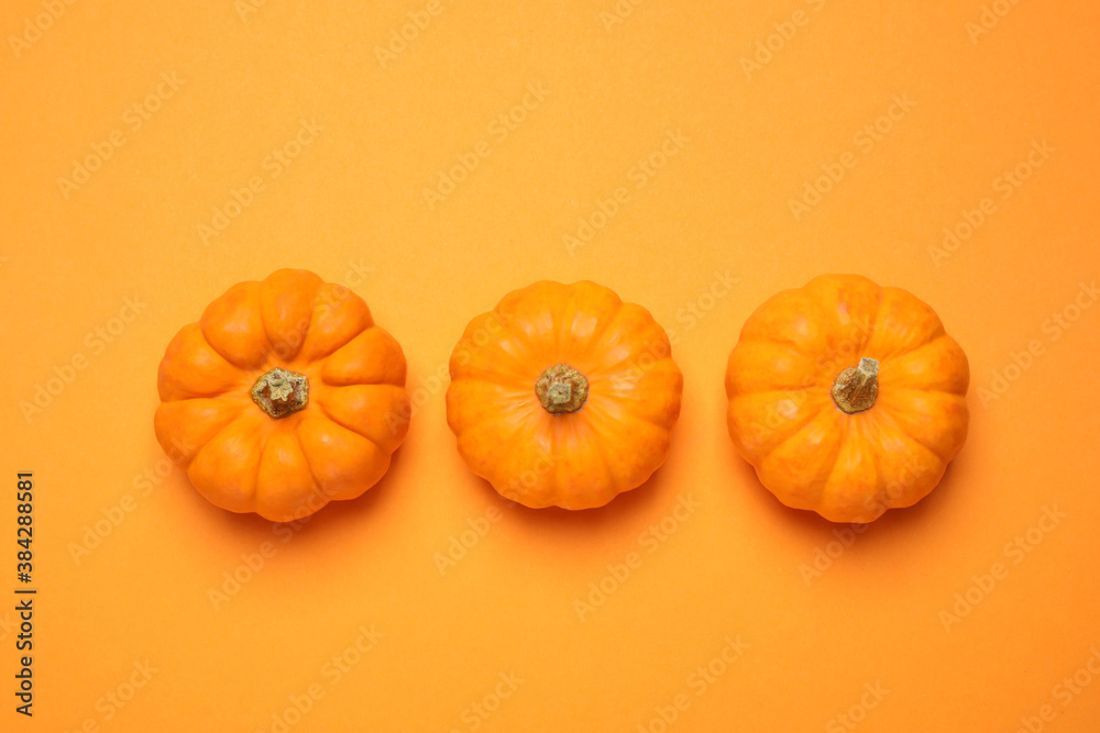 Fresh ripe pumpkins on orange background, flat lay