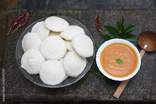 Indian idly served on traditional vegetarian food. Lots of many fresh steamed Indian Idly , Idli rice cake. South Indian breakfast idly sambar or Sambhar red coconut chutney