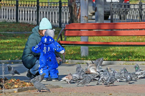 Mother and her little son feed city pigeons