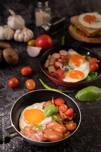 Breakfast with fried eggs  sausage  and ham in a pan with tomatoes. Chili and basil.