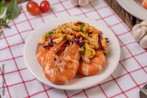 Fried shrimp with eggs in a white plate placed on a cloth with a fork.