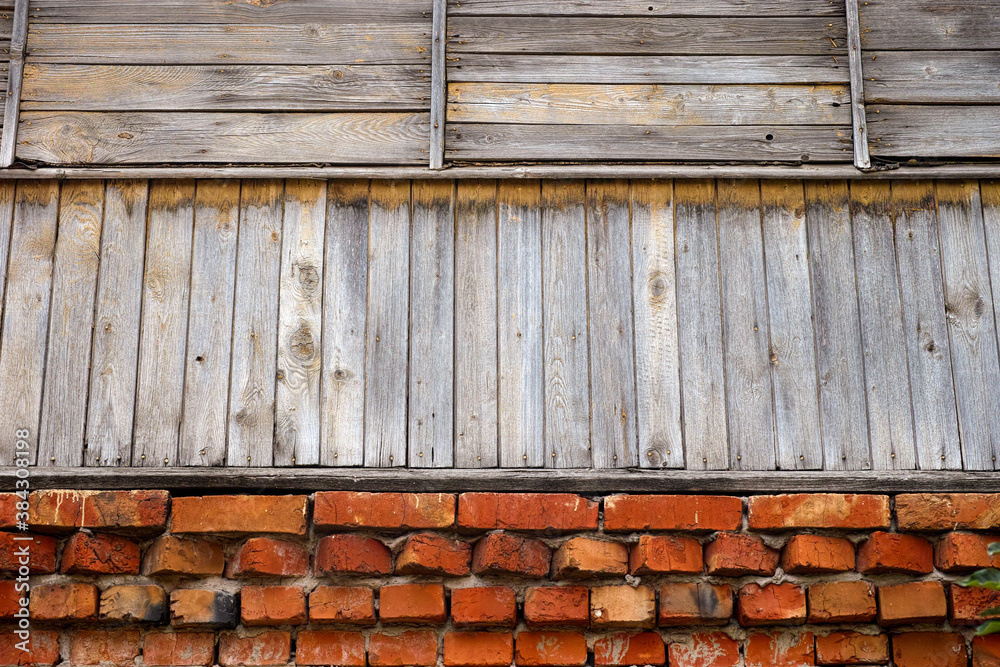 Fototapeta premium Wall of an old building- red bricks on the bottom and wooden planks on top
