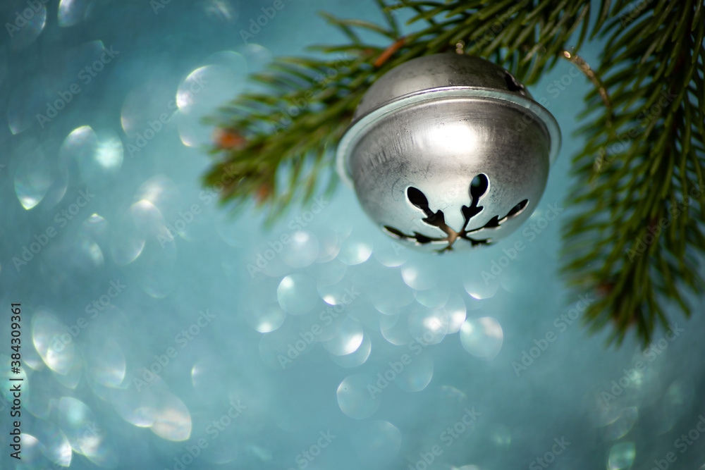 Fototapeta premium Bell on a Christmas tree branch on a blue background with bokeh