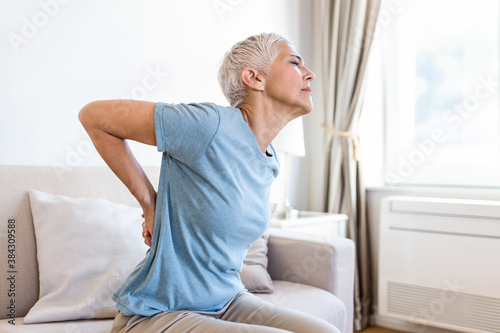Matur Woman suffering from lower back pain. Mature woman resting with back pain. Female lower back pain. Senior woman injury suffering from backache photo
