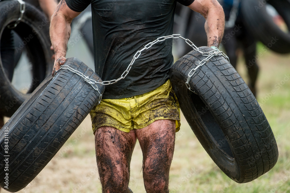 Fototapeta premium Mud race runner, man running in mud. Runners during extreme obstacle races. Active life and sport concept.