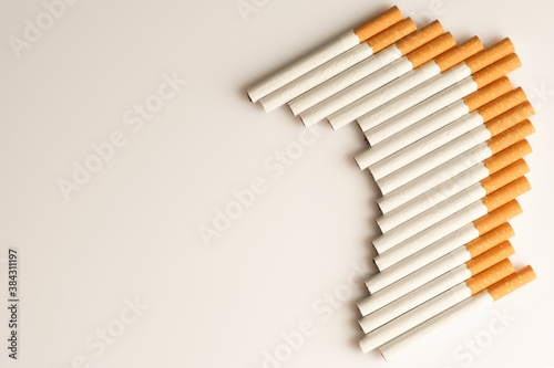 Cigarettes with a yellow filter lie on a white surface