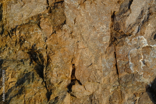 Background from a stone of igneous rock. Wallpaper made of textures of boulders of volcanic origin. Surface of granite, diabase, gabbro interspersed with spar, quartz. Sea shore. Day. Georgia.