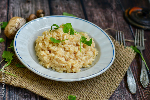 Italian creamy  mushroom  cheese risotto with parmesan cheese and fresh basil on rustic background
