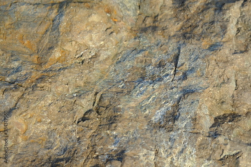 Background from a stone of igneous rock. Wallpaper made of textures of boulders of volcanic origin. Surface of granite, diabase, gabbro interspersed with spar, quartz. Sea shore. Day. Georgia.