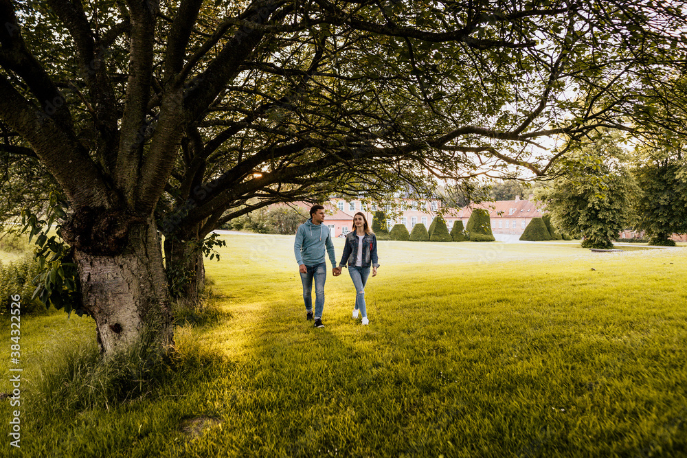 Horizontal photo of romantic couple walking near big tree with nature background Horizontal photo of romantic couple walking near big tree with nature background