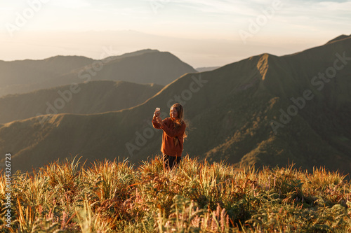 Young woman hiker use smartphone taking photo on  mountain top photo