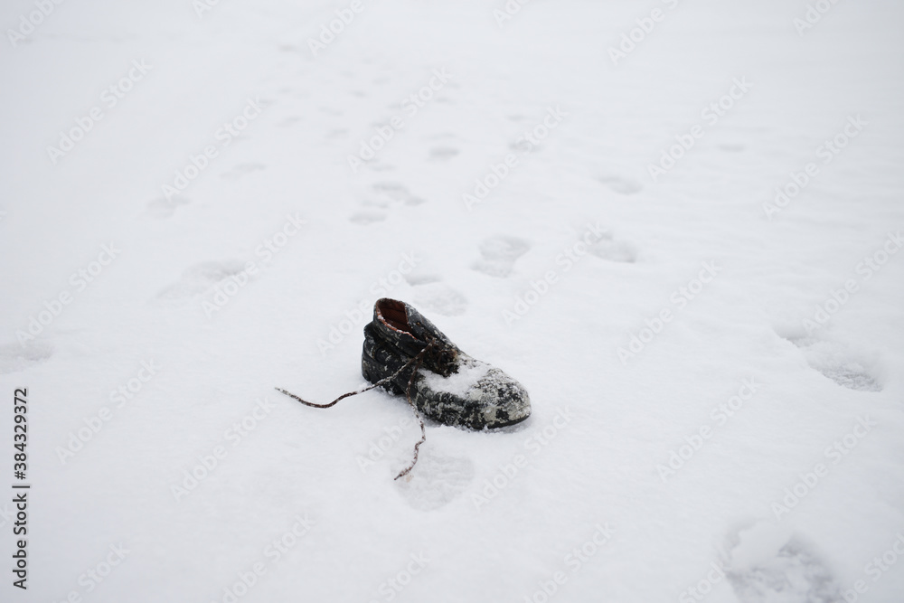 Old shoe forgotten in winter, covered with snow, snow tracks. Man lost a shoe in the snow in winter time, lost abandoned piece of cloth Old shoe forgotten in winter, covered with snow, snow tracks. Man lost a shoe in the snow in winter time, lost abandoned piece of cloth