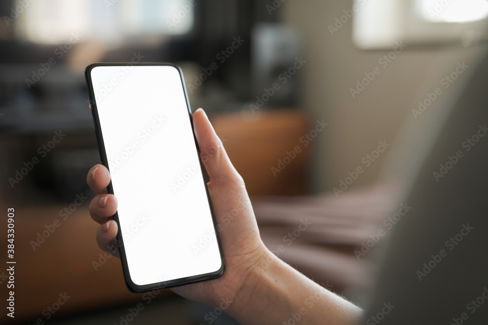 Young woman hold smartphone with white screen while sitting on a couch