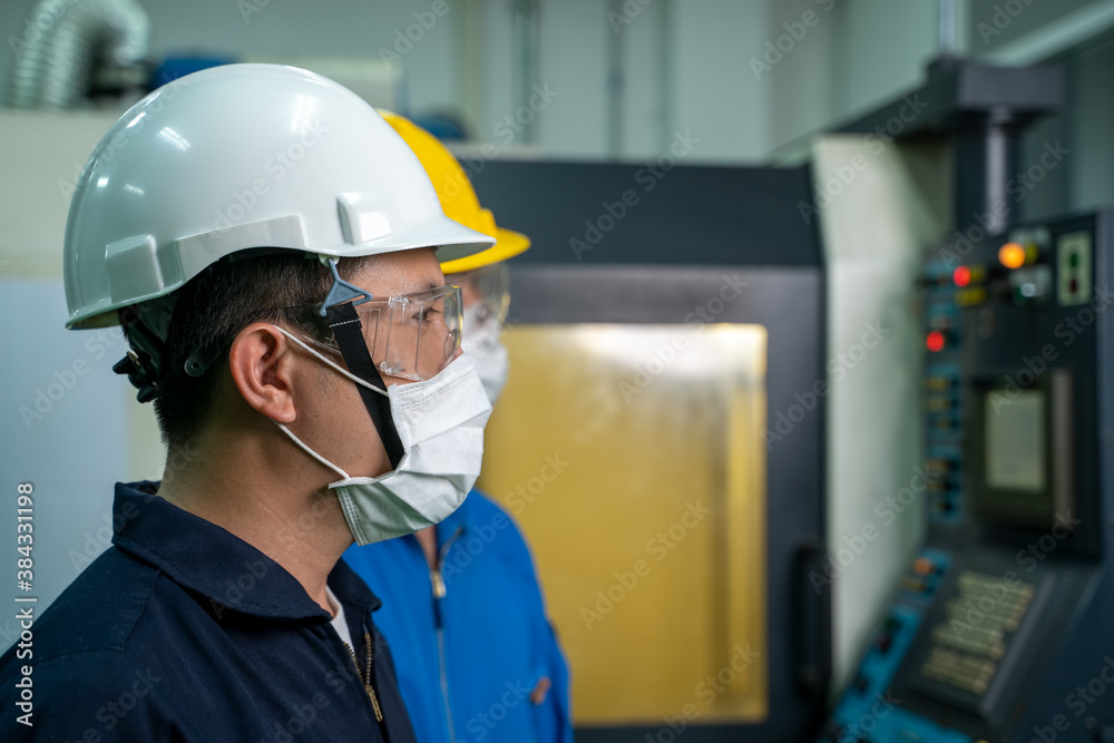 Engineer mechanic wearing protective mask to Protect Against Covid-19 working in a large industrial factory. Engineer mechanic wearing protective mask to Protect Against Covid-19 working in a large industrial factory.