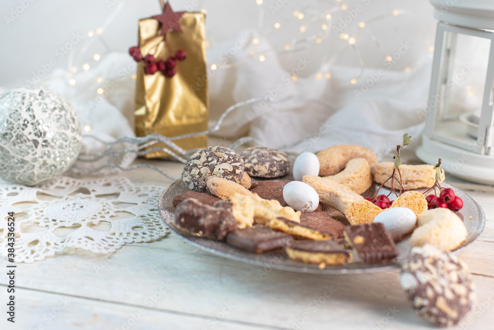 Fototapeta premium a white wooden table with white Christmas decorations and a plate of homemade cookies