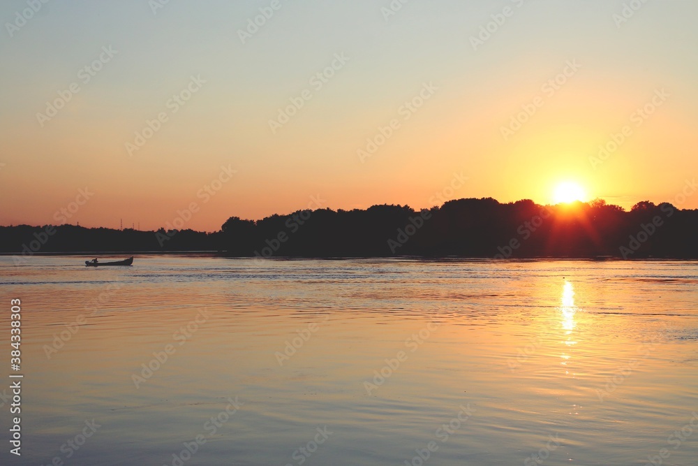 La silueta de un bote navegando por el río Danubio. Delta del Danubio al atardecer a su paso junto a Nufaru, Rumanía.