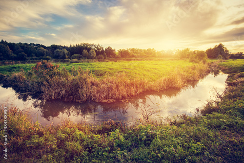 Countryside with small river at sunset.