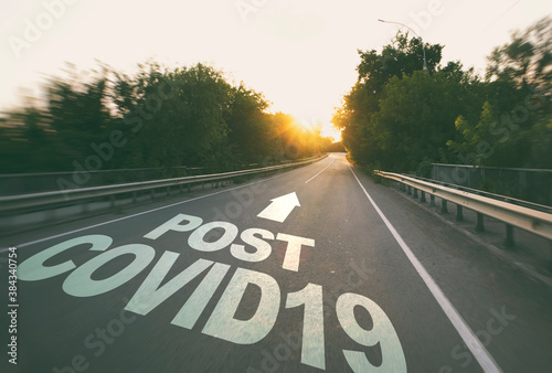 The empty road in the forest and the text on the asphalt "Post covid19".