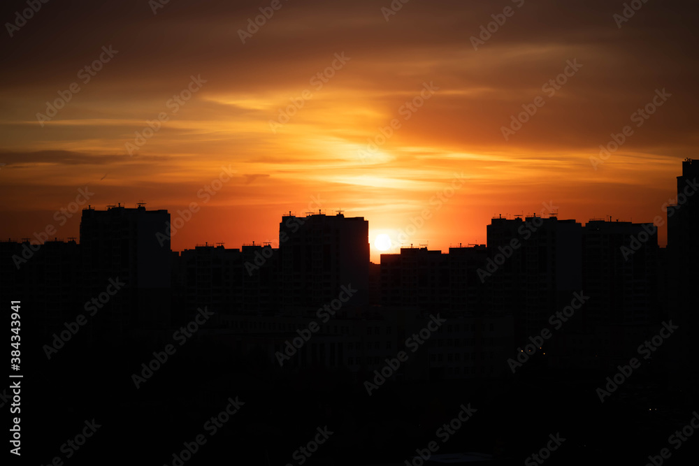 Big city in the rays of the sunset. High-rise black houses and red fiery sky.