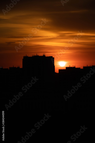 Big city in the rays of the sunset. High-rise black houses and red fiery sky.