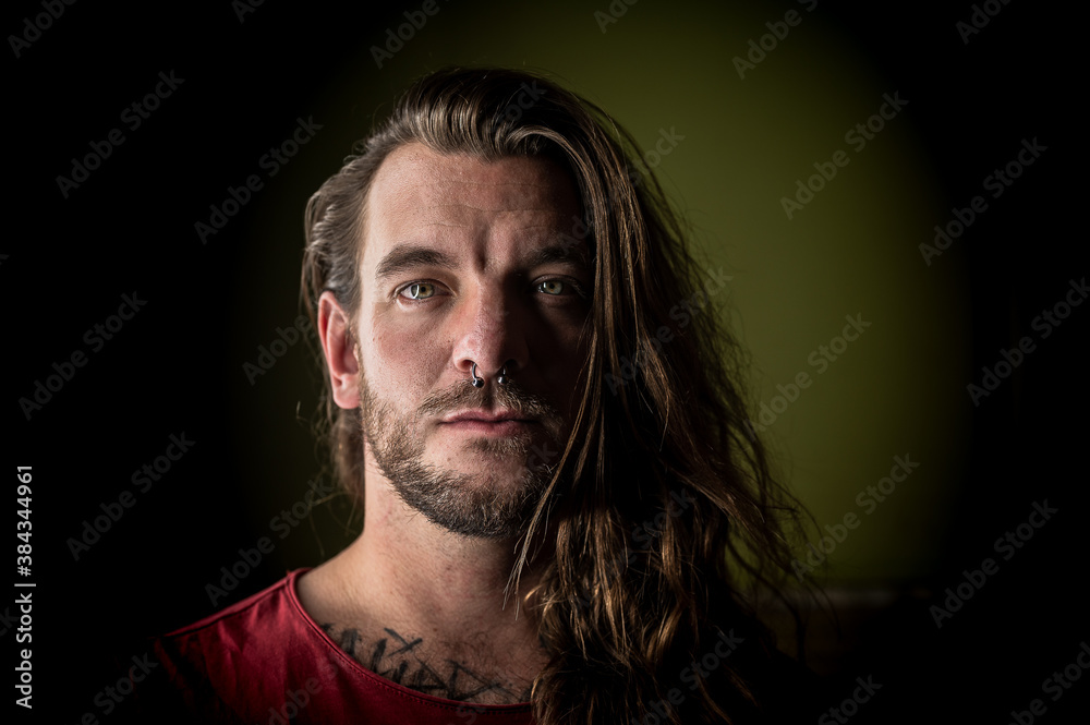 Man with long hair looks seriously at the camera