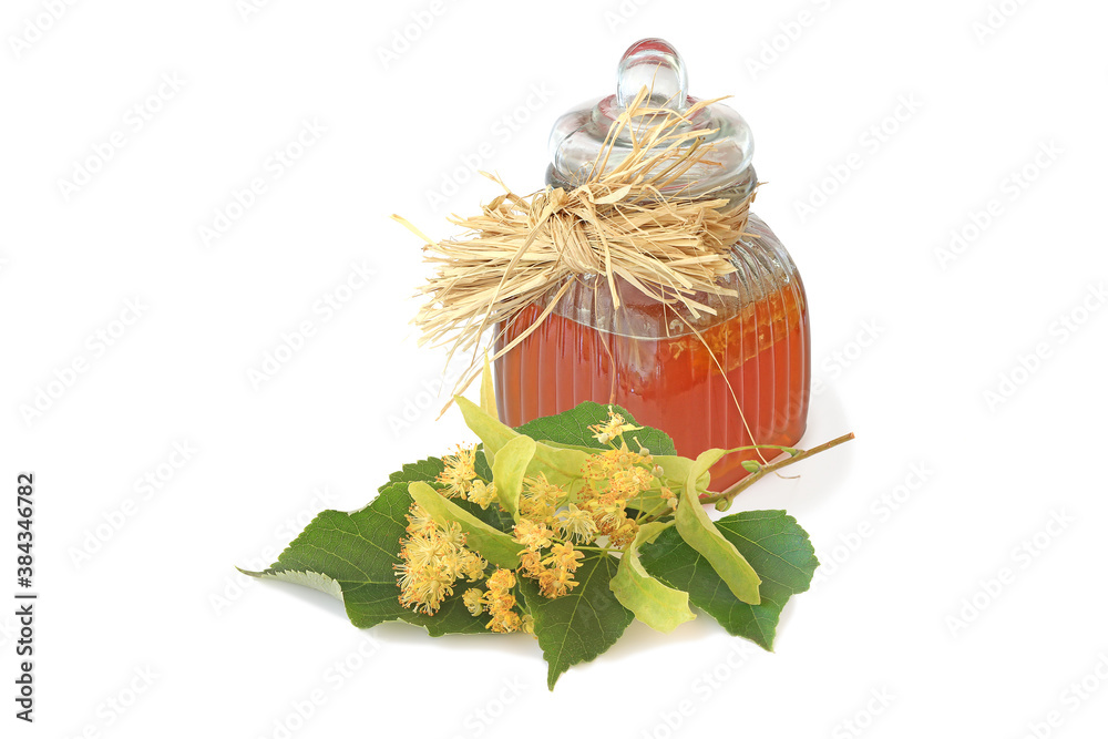 Jar of tasty linden honey and flowering sprig of linden on white