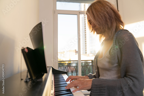 in a bright room with a large window, a woman plays the electronic forteiano