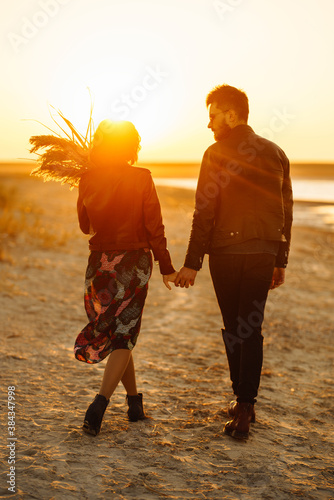 Romantic couple enjoying beautiful sunset walk on the beach travel autumn vacation. Enjoying time together. The concept of youth, love and lifestyle.