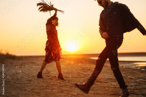 Romantic couple enjoying beautiful sunset walk on the beach travel autumn vacation. Enjoying time together. The concept of youth, love and lifestyle.