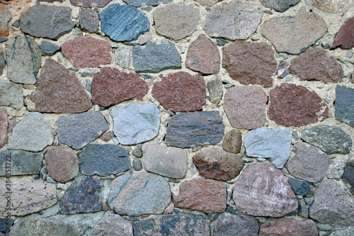 The wall of the building is made of chipped stone on a mortar. Beautiful texture