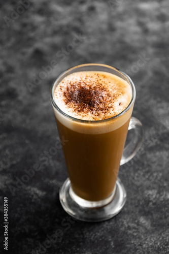 Hot chocolate drink. Tall glass up of fresh coffee latte with whipped cream, isolated on dark background